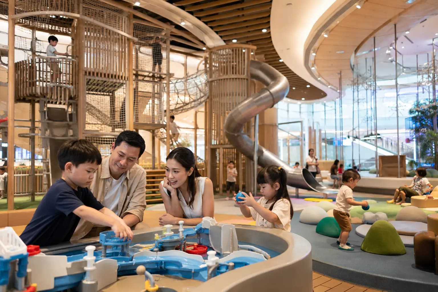 Children playing on interactive climbing and discovery play structures inside a conceptual indoor family venue.
